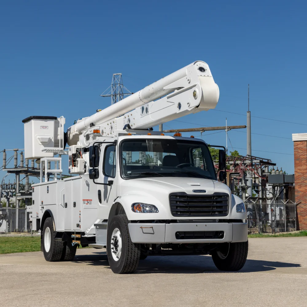 Freightliner utility truck equipped with an extended boom crane parked near electrical substations